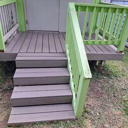 A wooden deck with stairs and a green railing.
