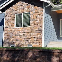 The front of a house with a stone wall and a window.
