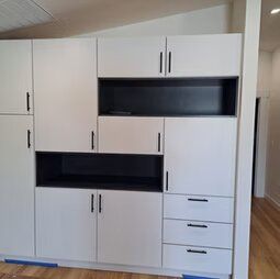 A large white cabinet with drawers and doors in a room.