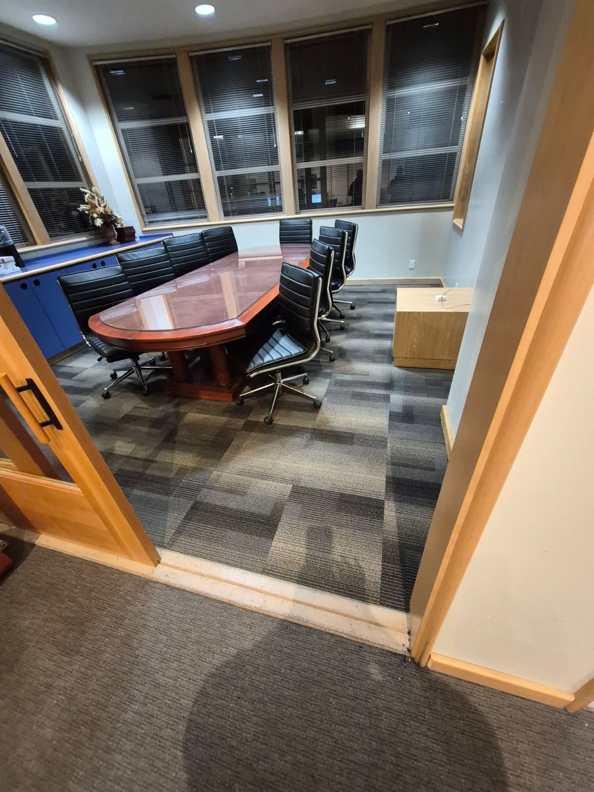 Conference room with large wooden table, chairs, and windows.