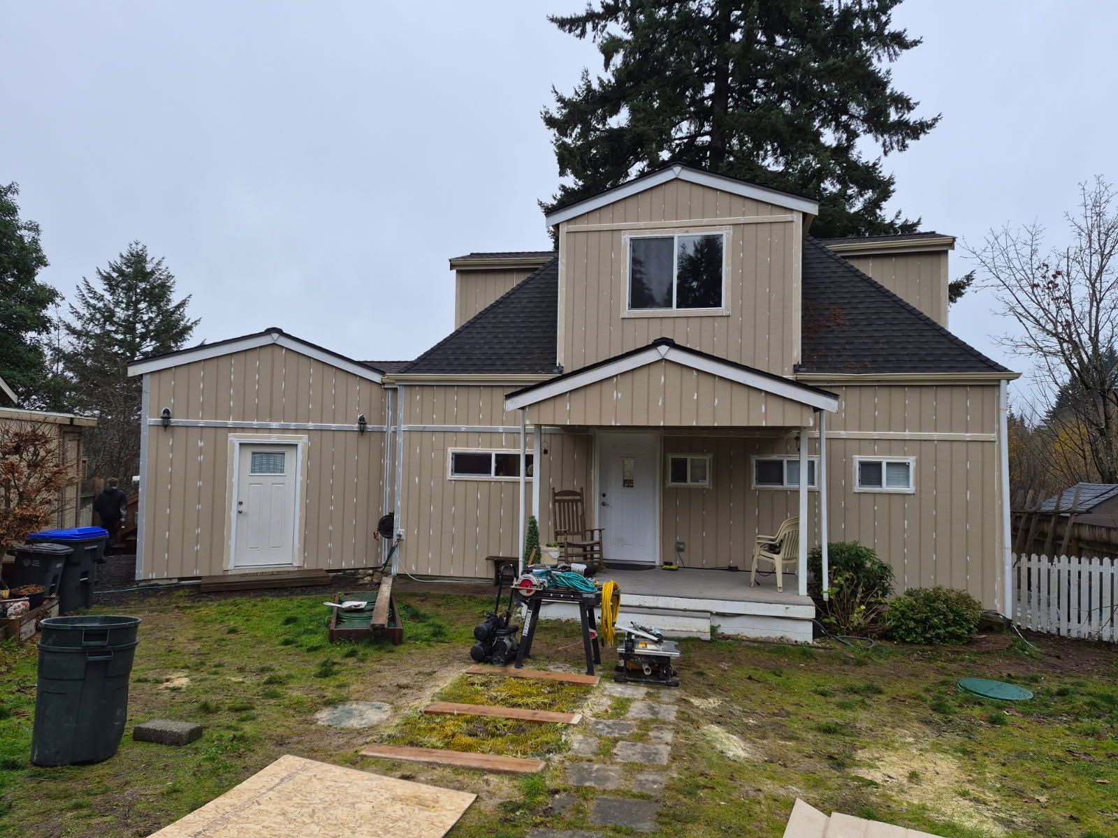 Teal house with a deck; rocking chairs sit outside a door and windows. Blue sky overhead.