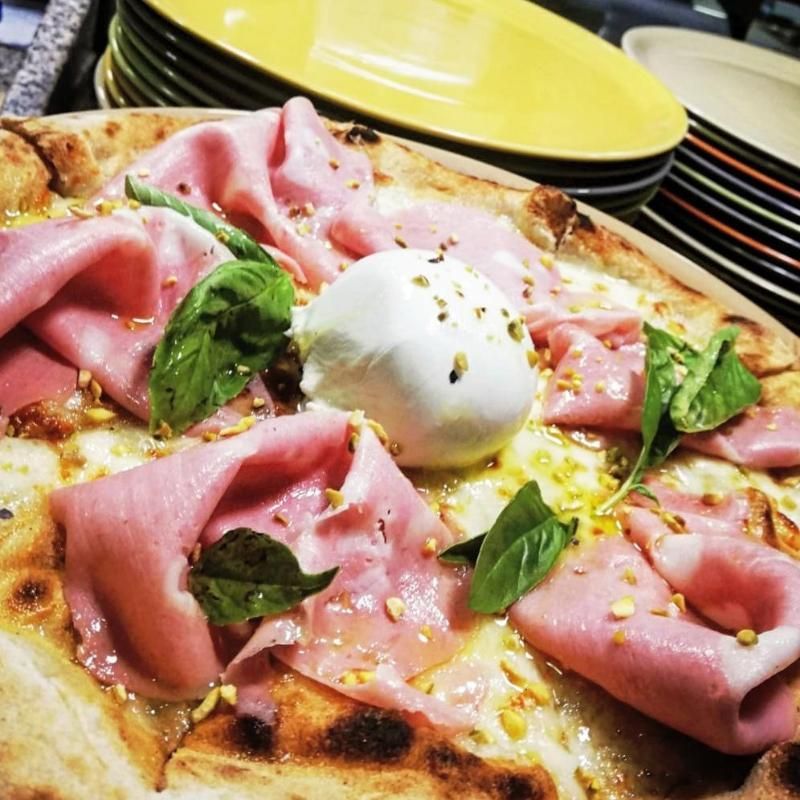 Una pizza con prosciutto e mozzarella sopra