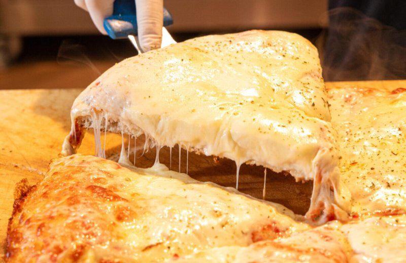Una persona sta tagliando una fetta di pizza su un tagliere.