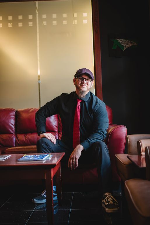 A man is sitting on a couch in a nice office setting.