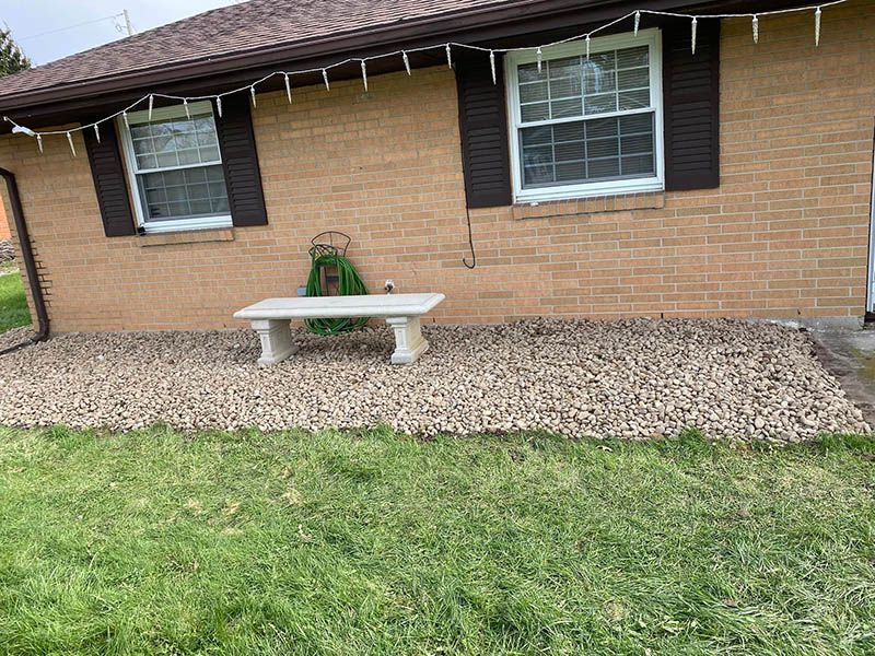 A brick house with a bench and a hose in front of it.