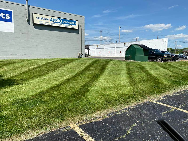 A lush green lawn is being mowed in front of a building.