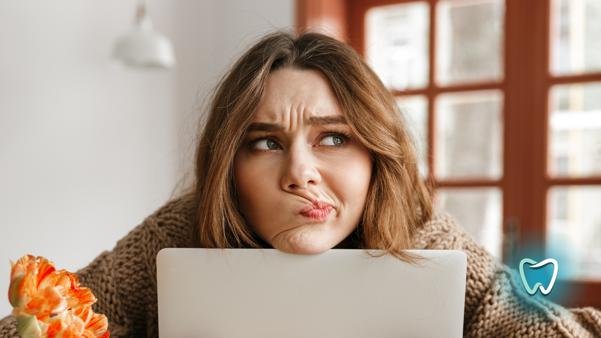 A woman is sitting at a table with a laptop and eating pizza.