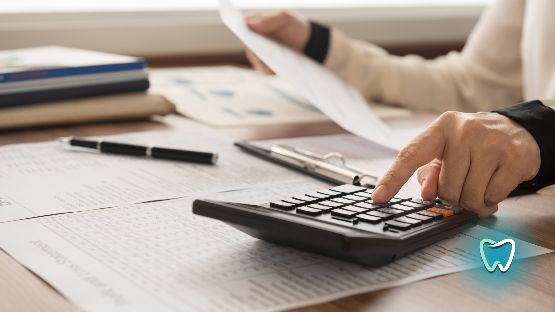 A person is using a calculator to calculate a dental bill.