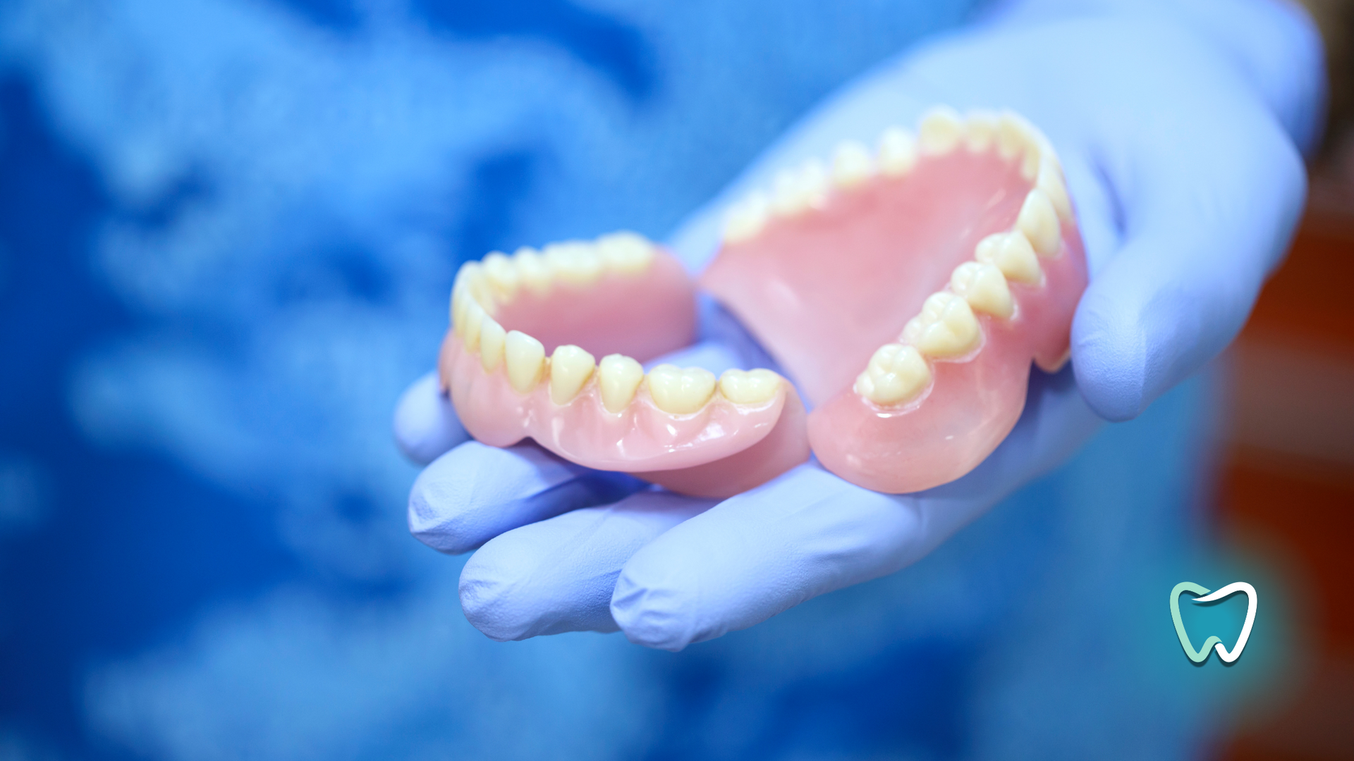 A person is holding a pair of dentures in their hand.