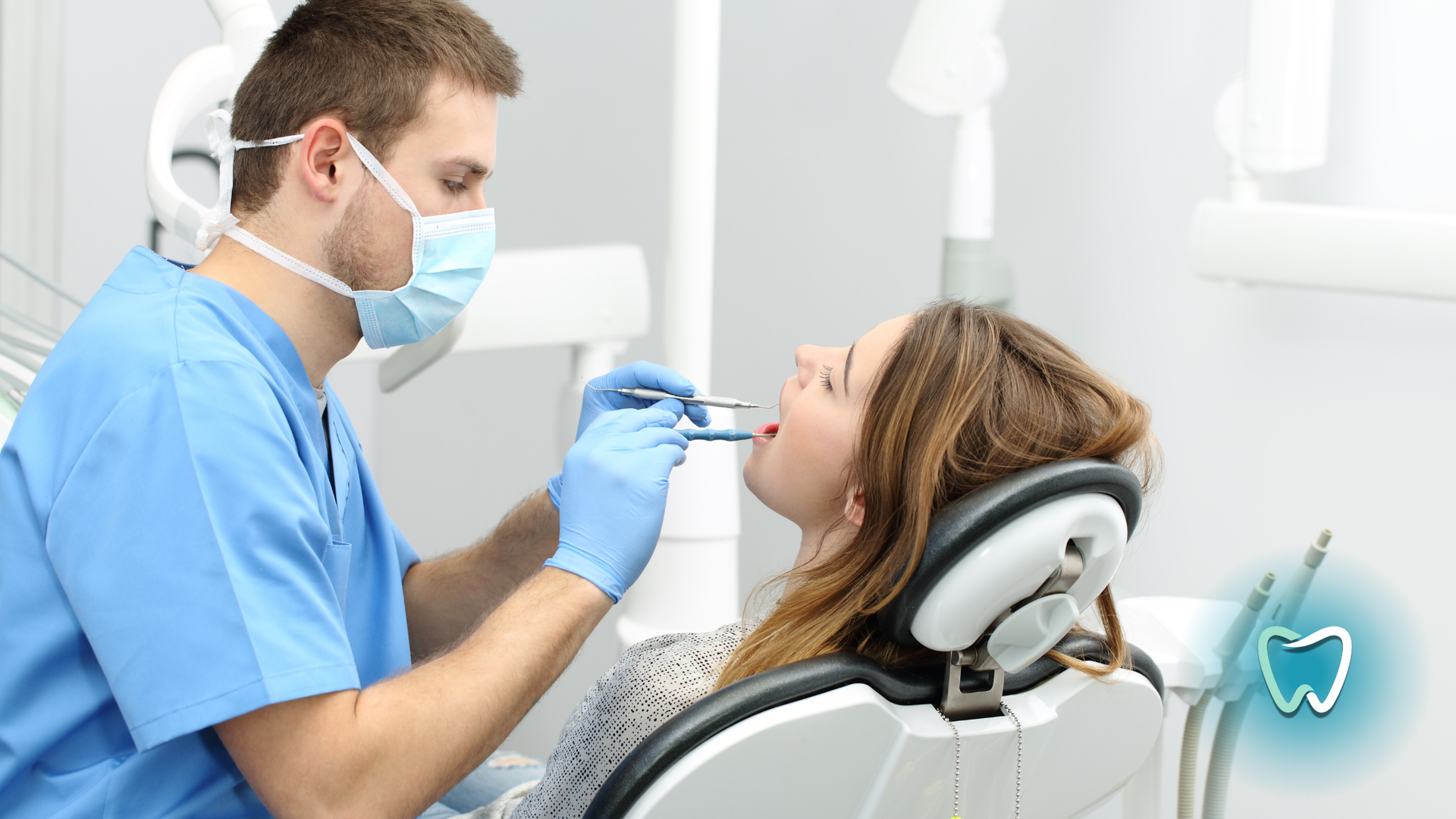 A woman is sitting in a dental chair while a dentist examines her teeth.