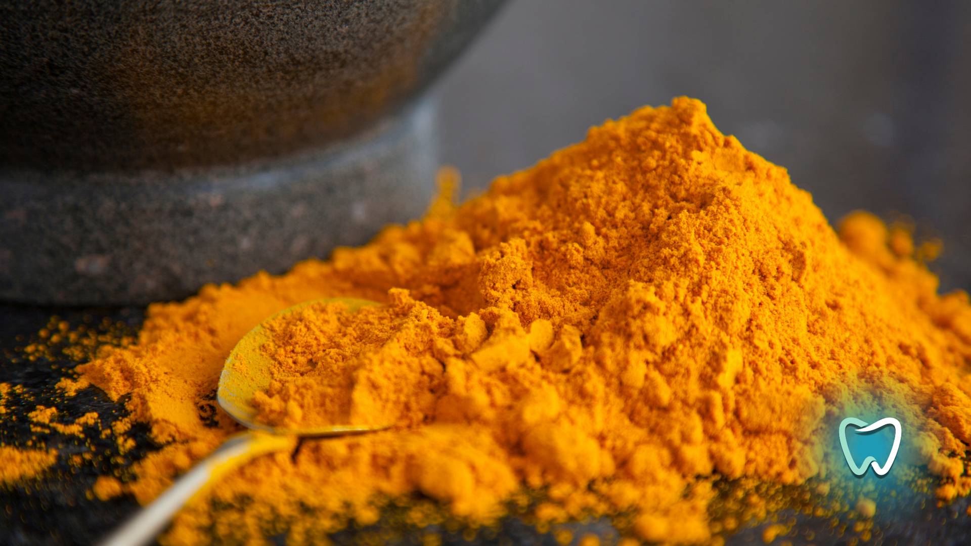 A pile of turmeric powder with a spoon in it.