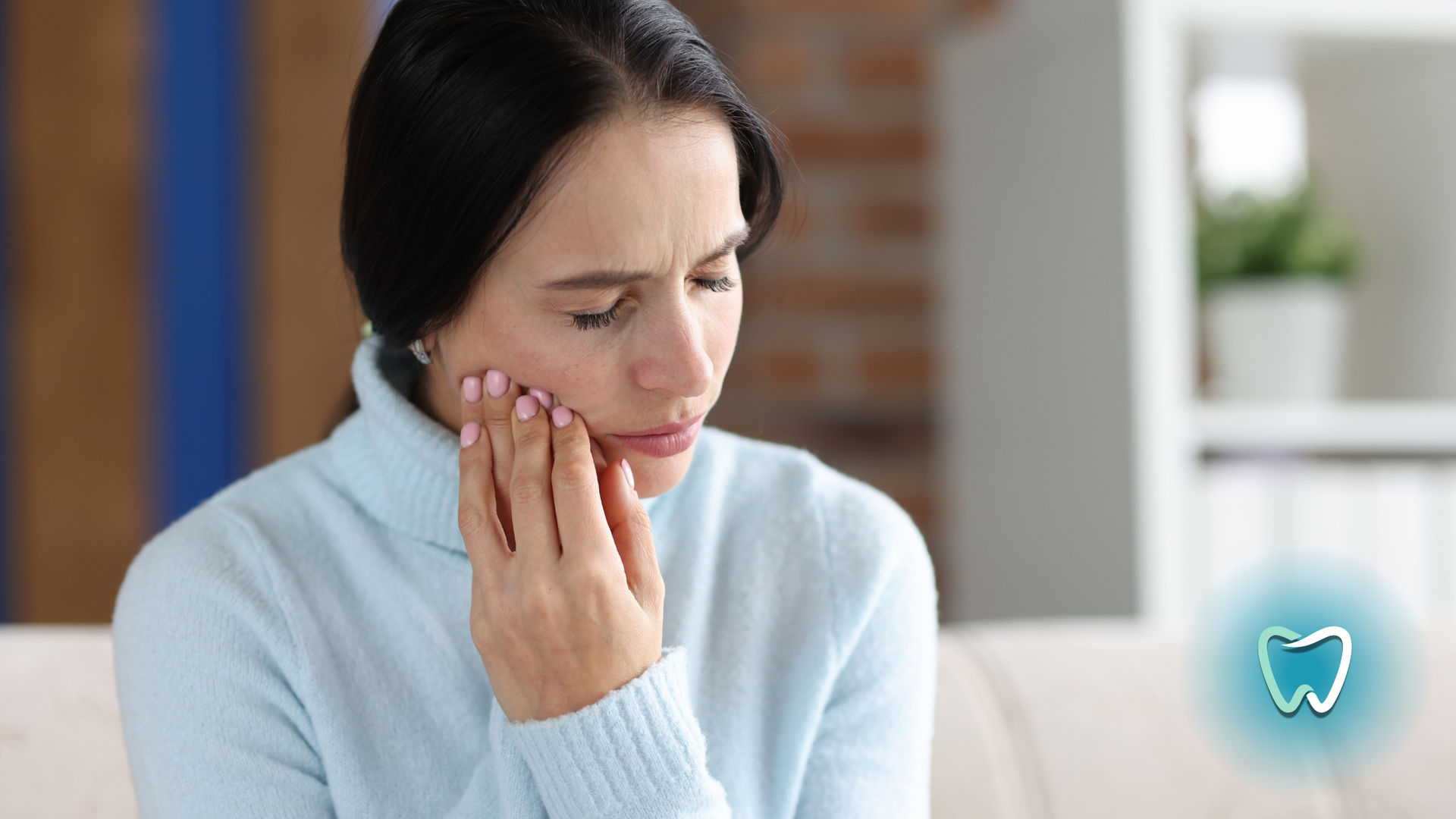 A woman is sitting on a couch with a toothache.