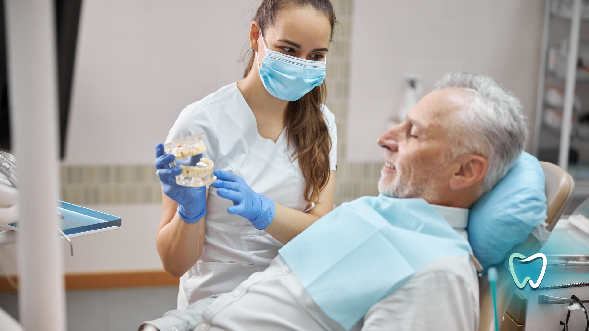 A woman is holding a model of a man 's teeth in a dental office.