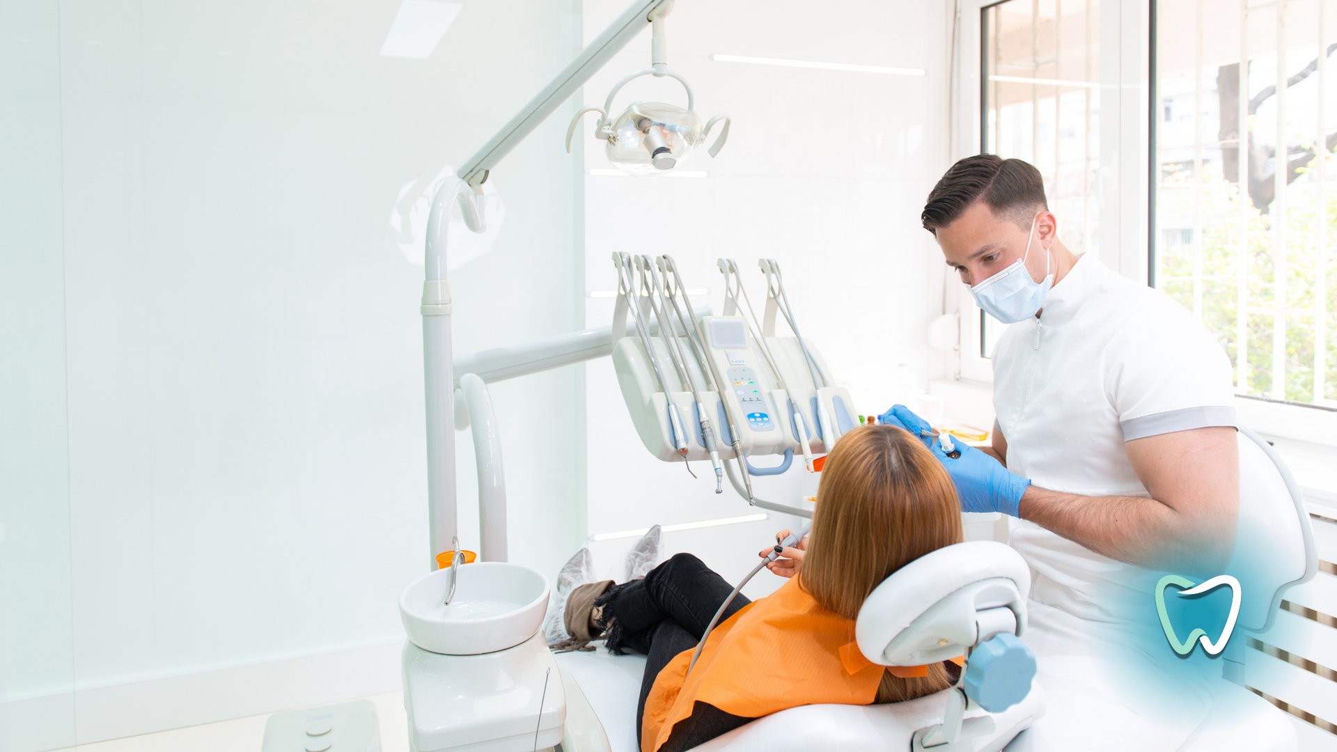 A woman is sitting in a dental chair while a dentist examines her teeth.
