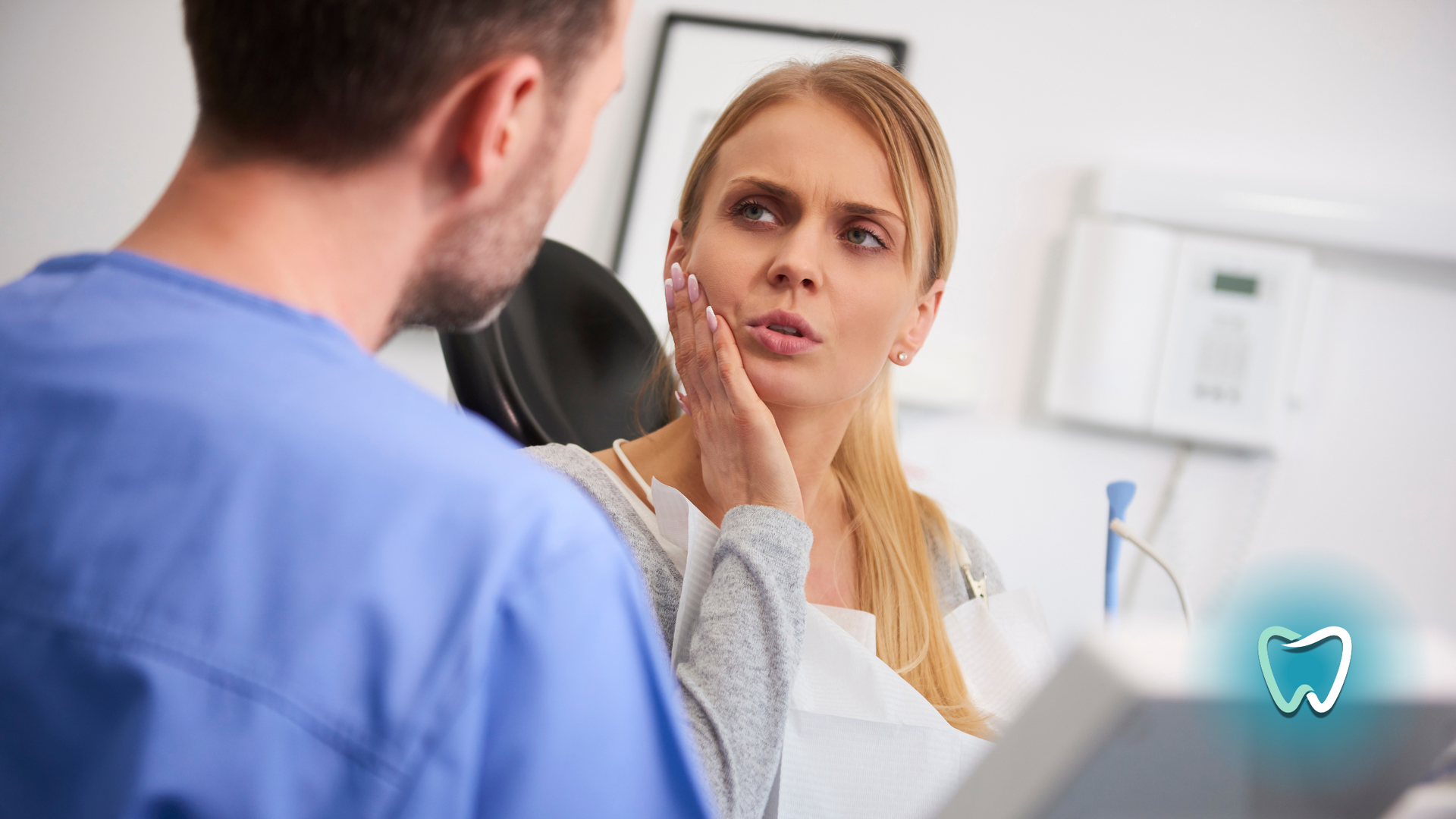 A woman is sitting in a dental chair talking to a dentist.