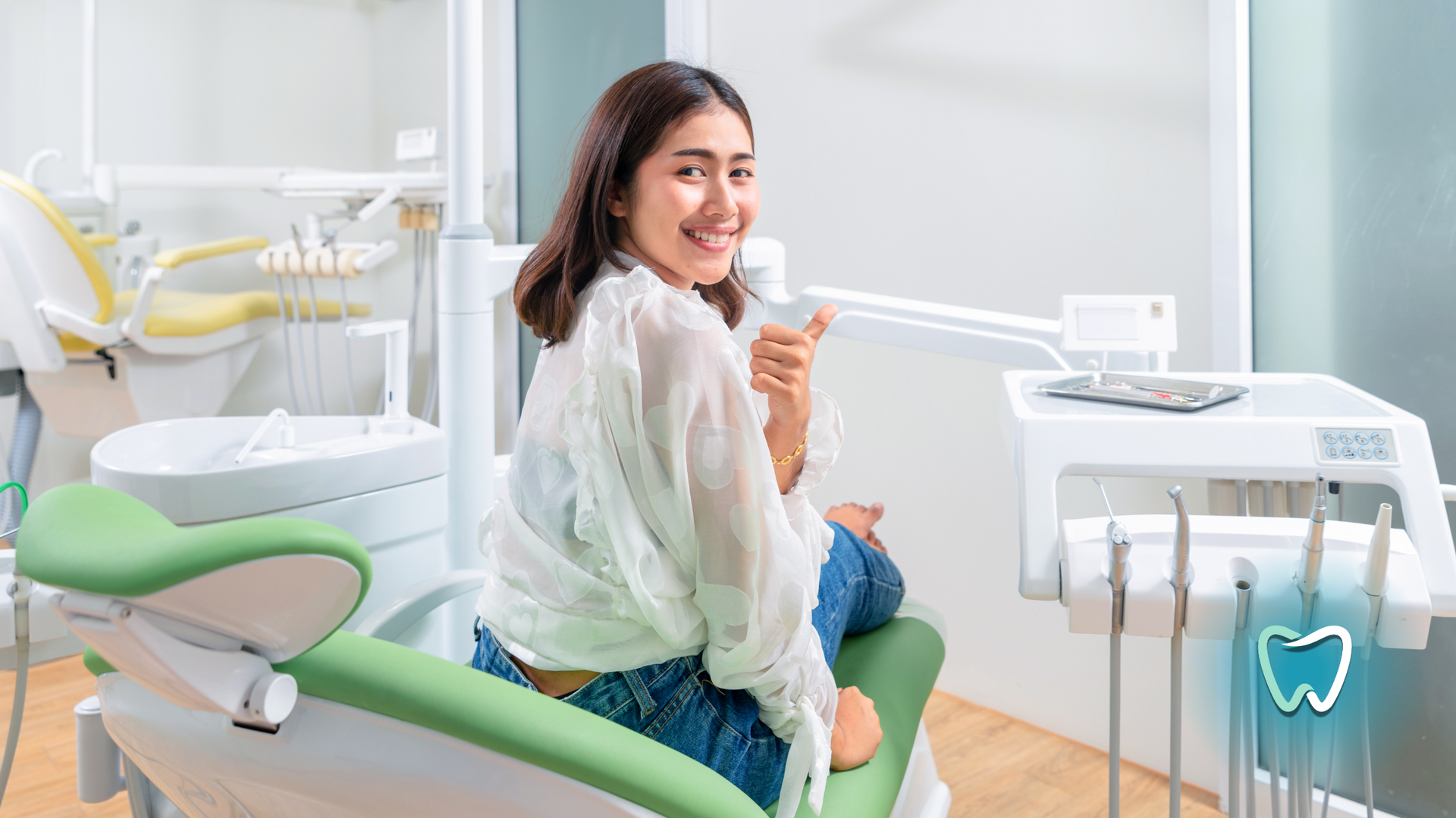 A woman is sitting in a dental chair and smiling.
