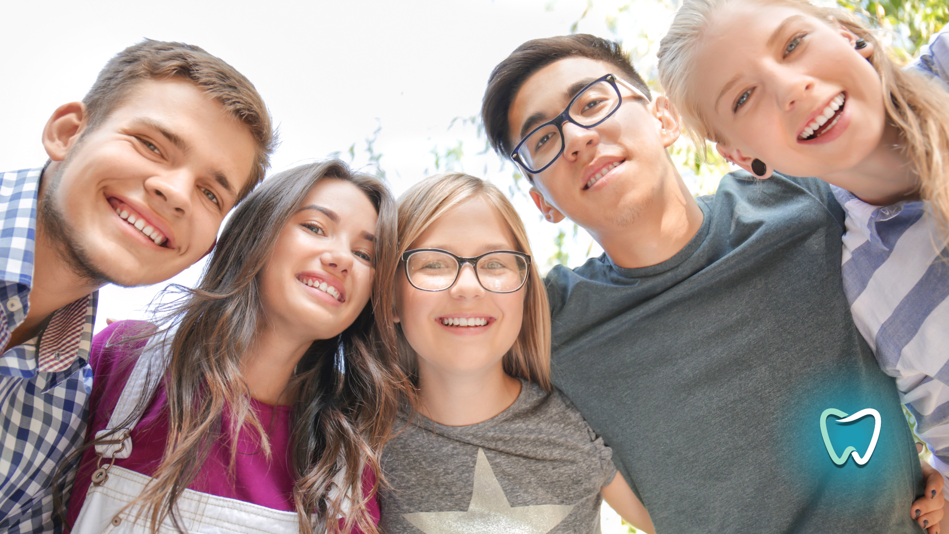 Smiling group of young people, outdoors, looking up. Teeth icon.
