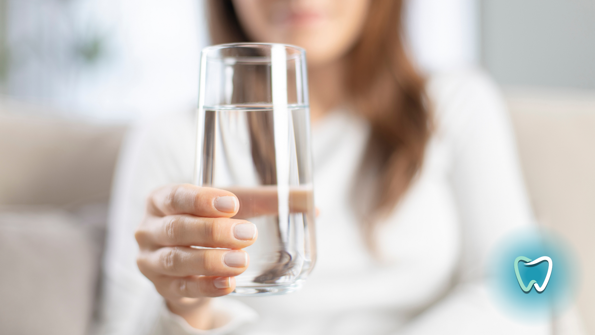 A woman is holding a glass of water in her hand.