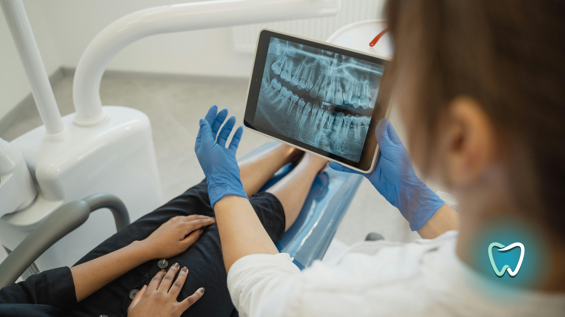 A dentist is looking at an x-ray of a child 's teeth on a tablet.