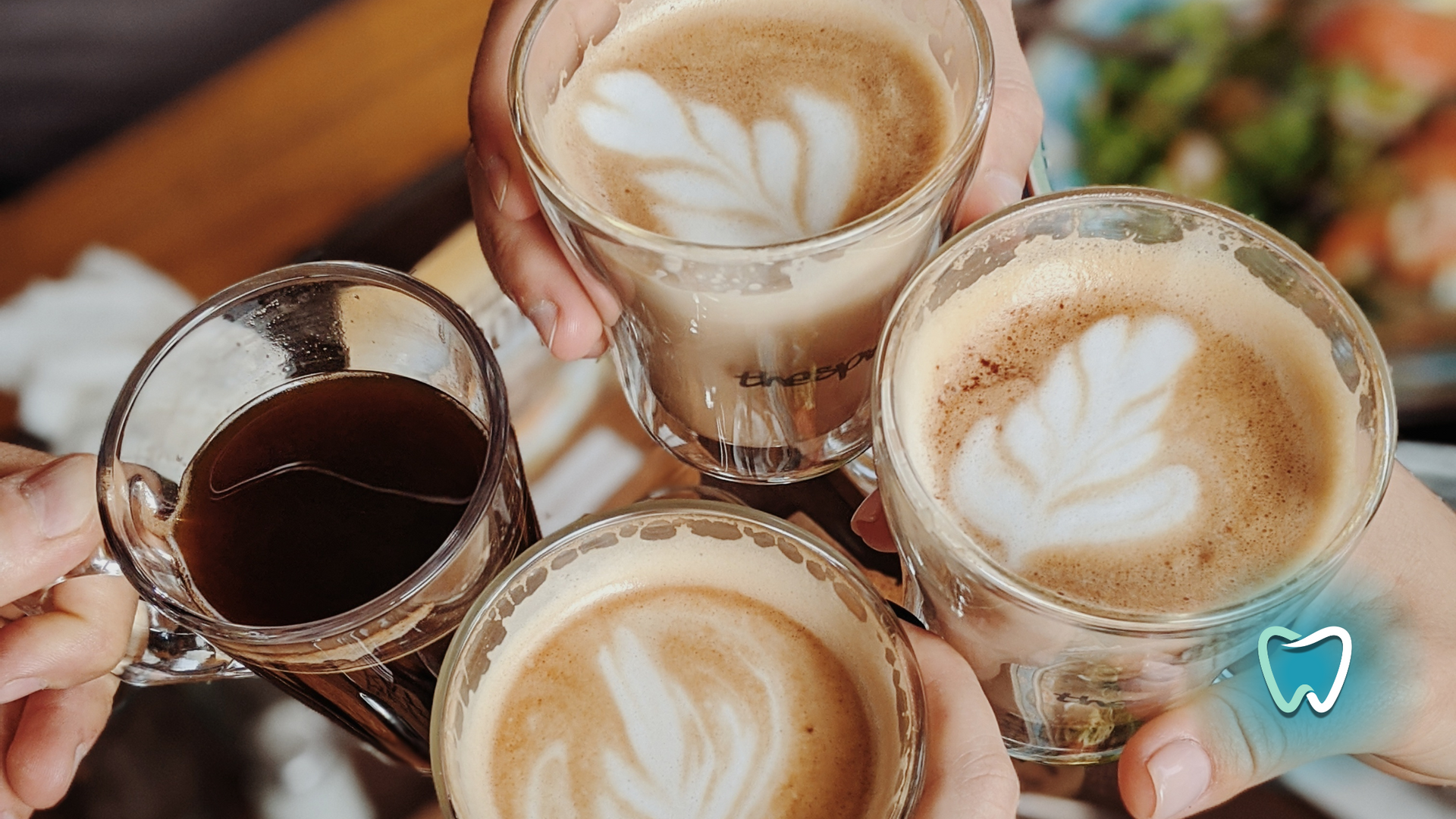 A group of people are toasting with four cups of coffee.