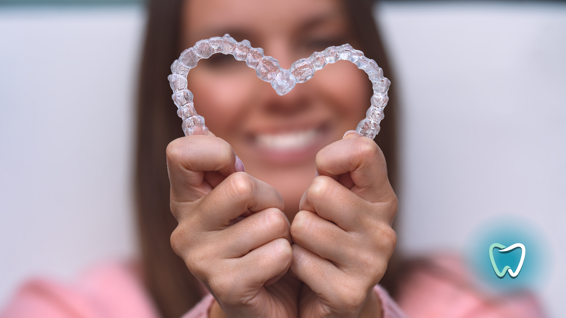 A woman is holding a heart shaped retainer in her hands.