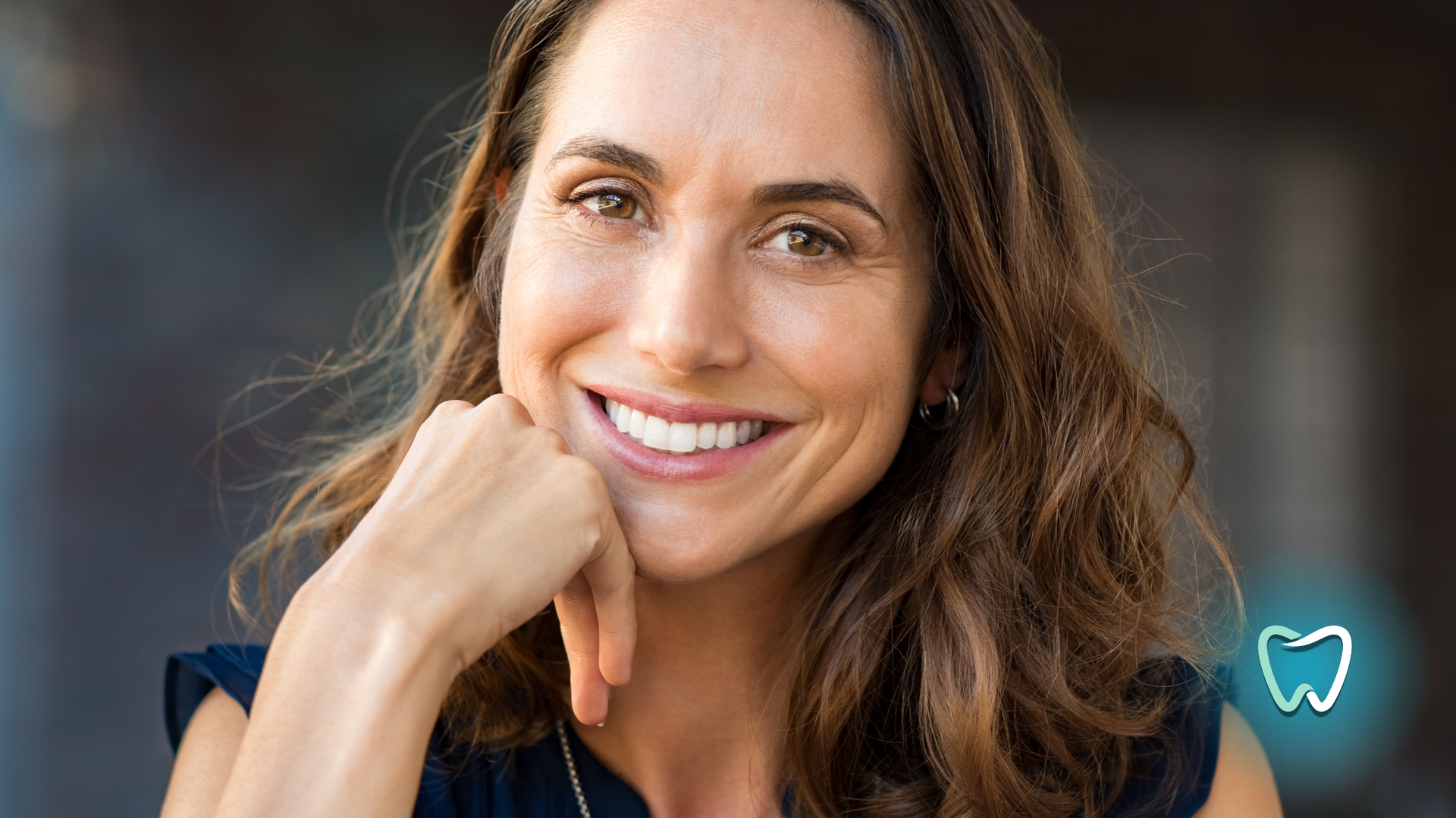 A woman is smiling with her hand on her chin.