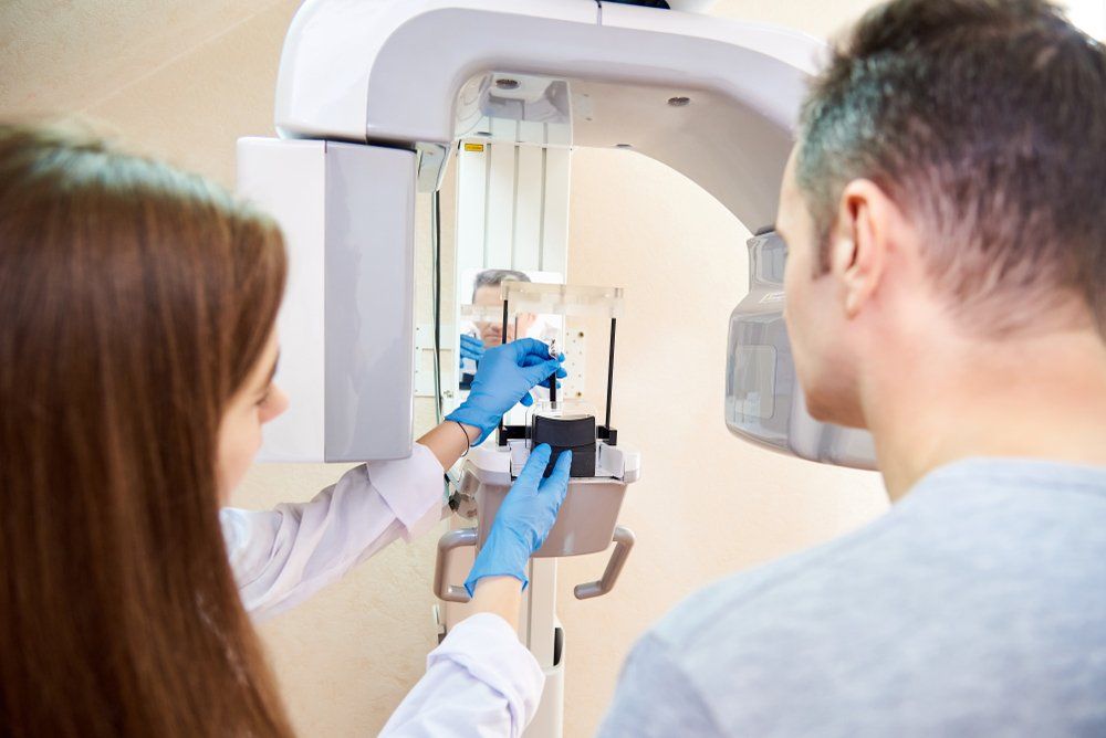 A man and a woman are getting an x-ray of their teeth in a dental office.