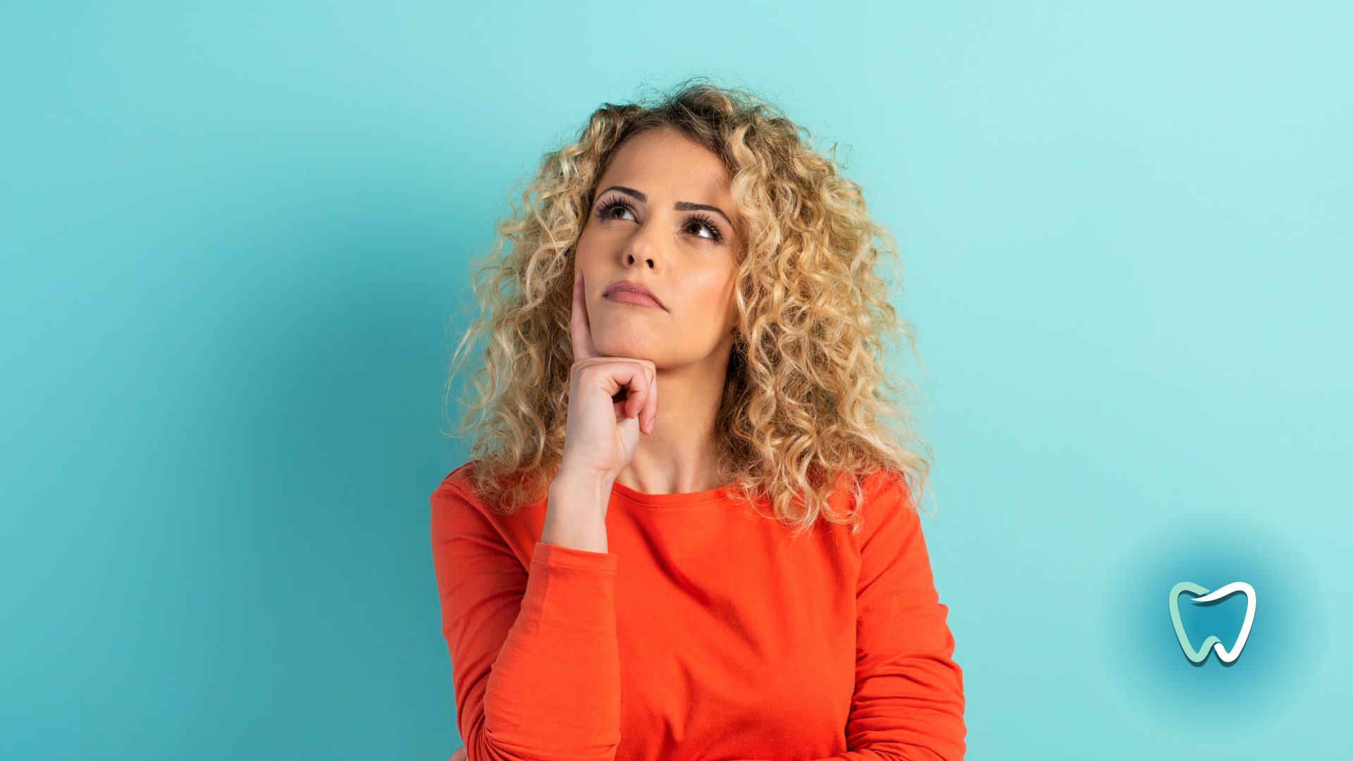 A woman in a red shirt is thinking about her teeth.