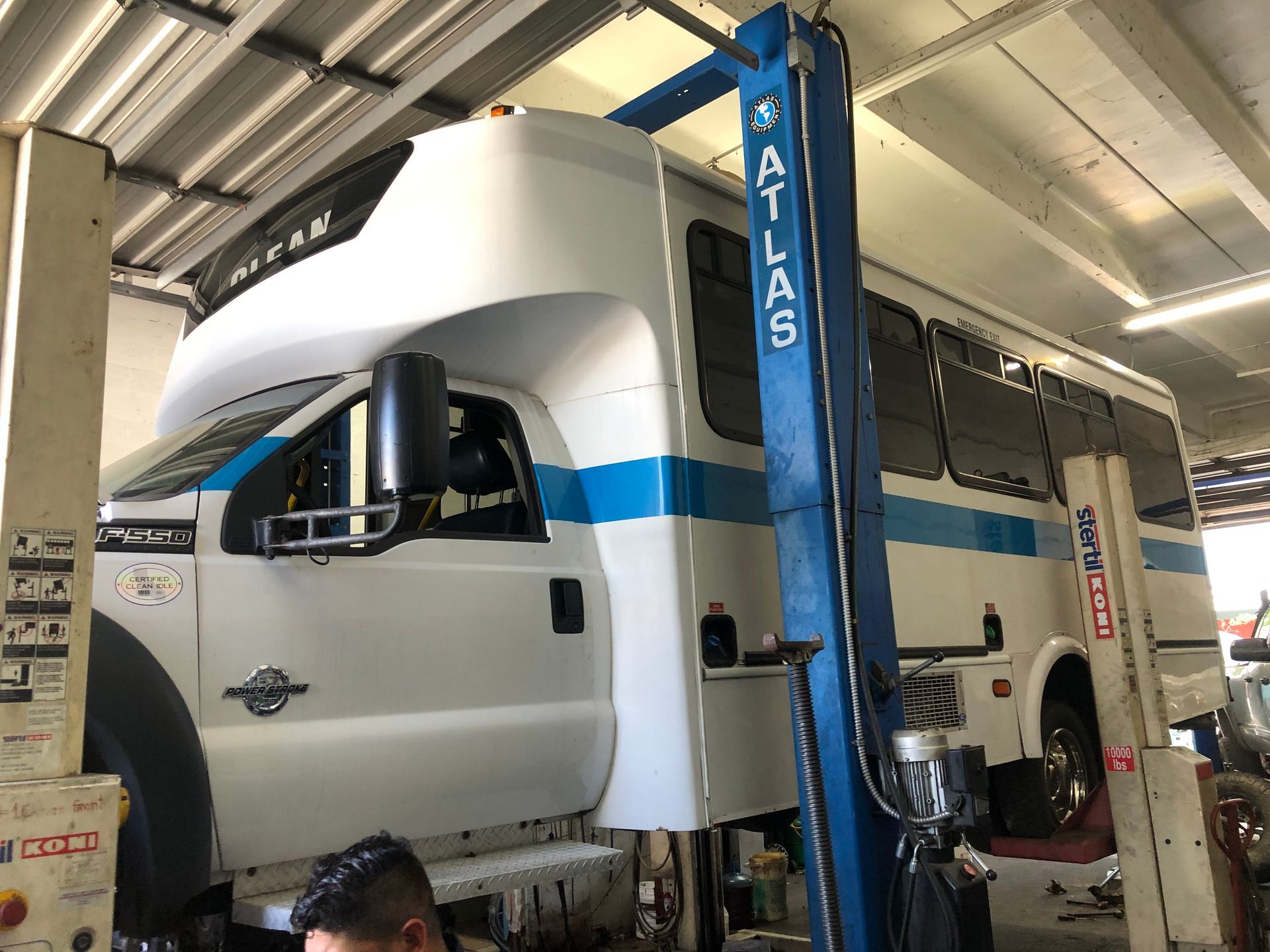 A bus is sitting on a lift in a garage.