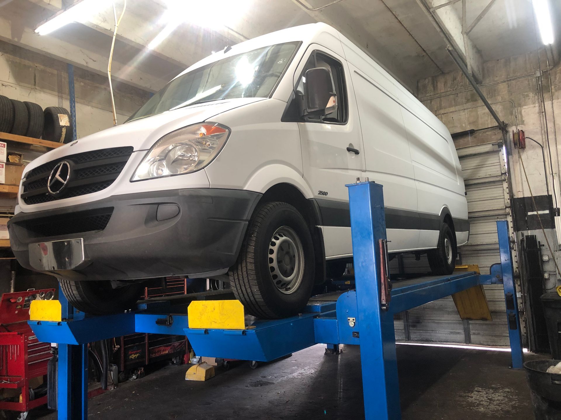 A white van is sitting on top of a blue lift in a garage.