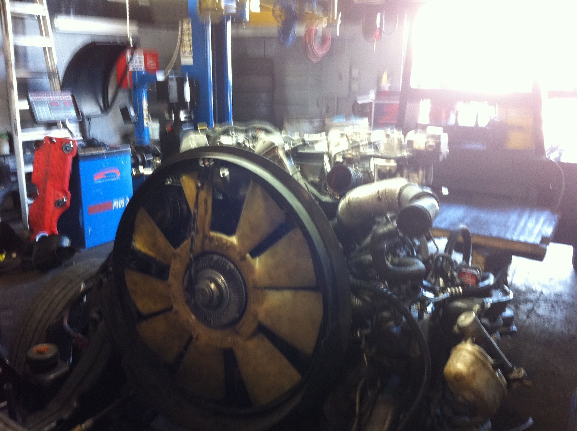 A large engine is sitting in a garage being worked on