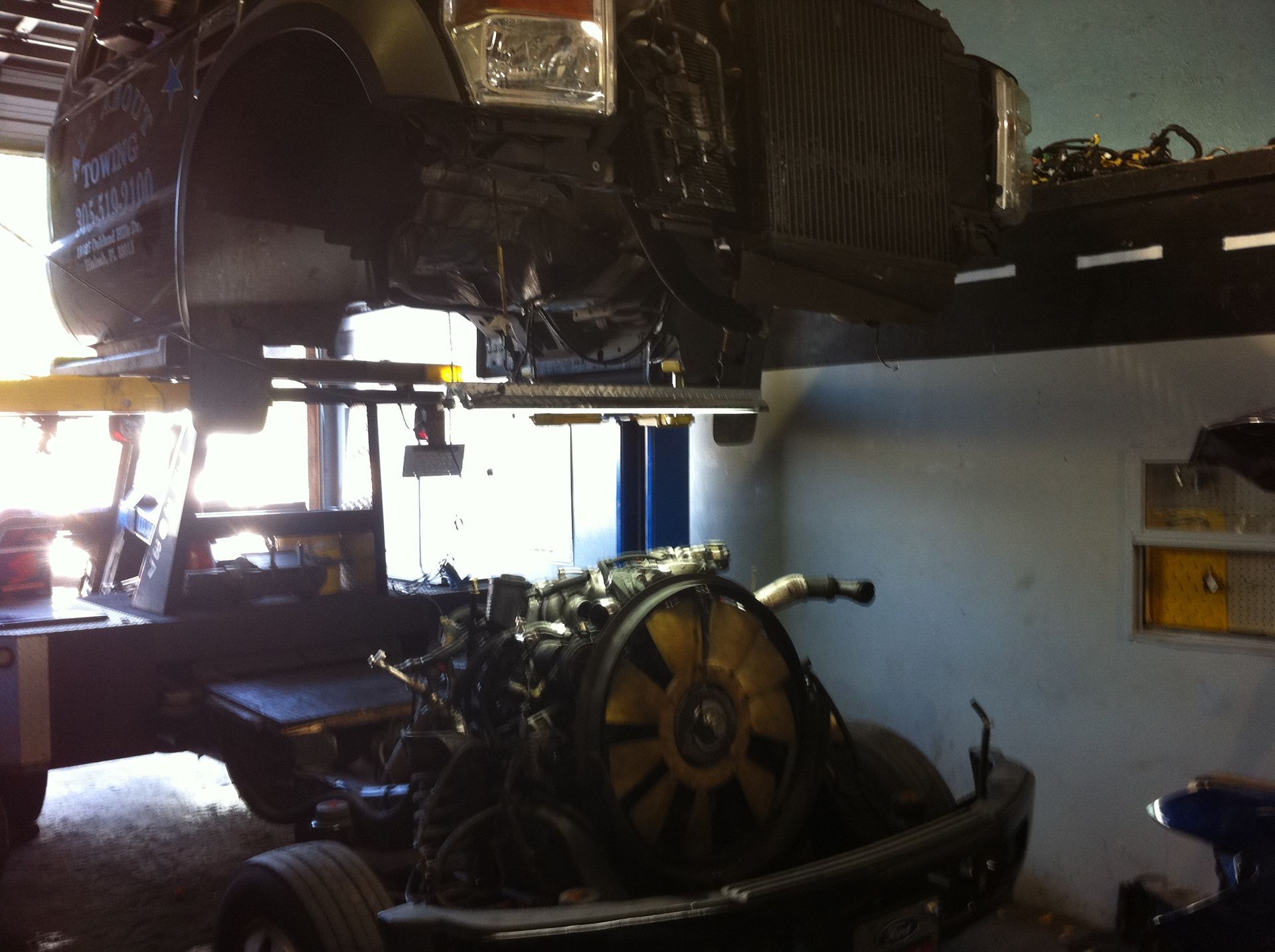 A car is being lifted in a garage with the engine exposed