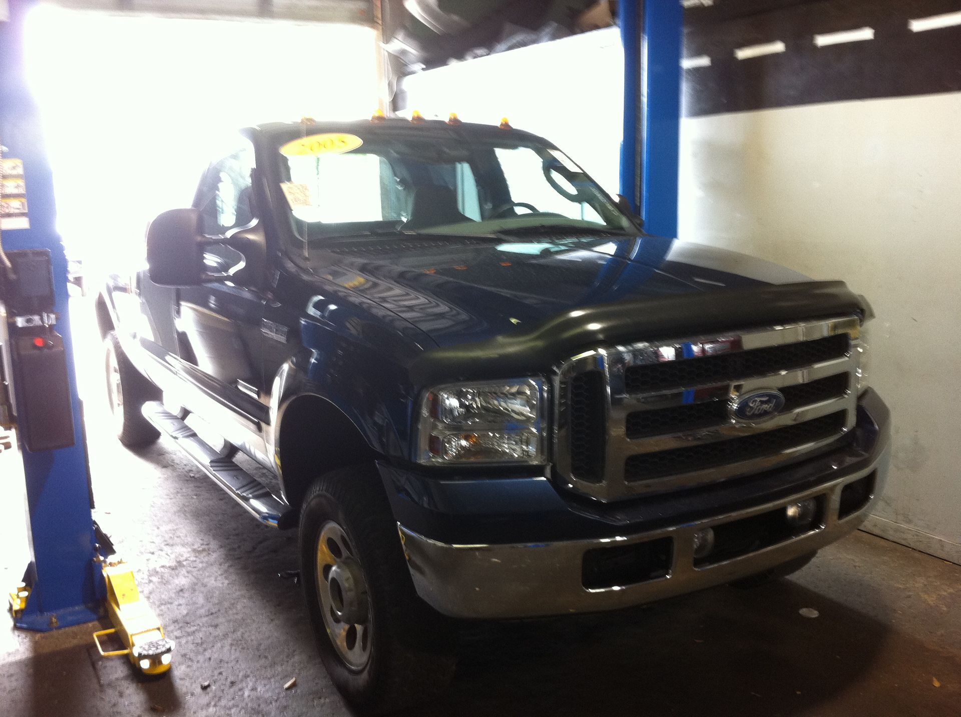 A ford truck is on a lift in a garage