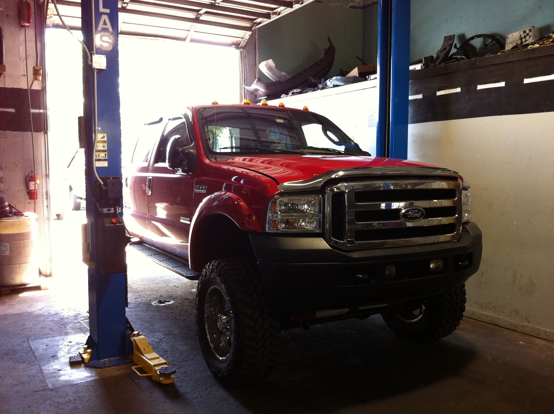 A red ford truck is on a lift in a garage