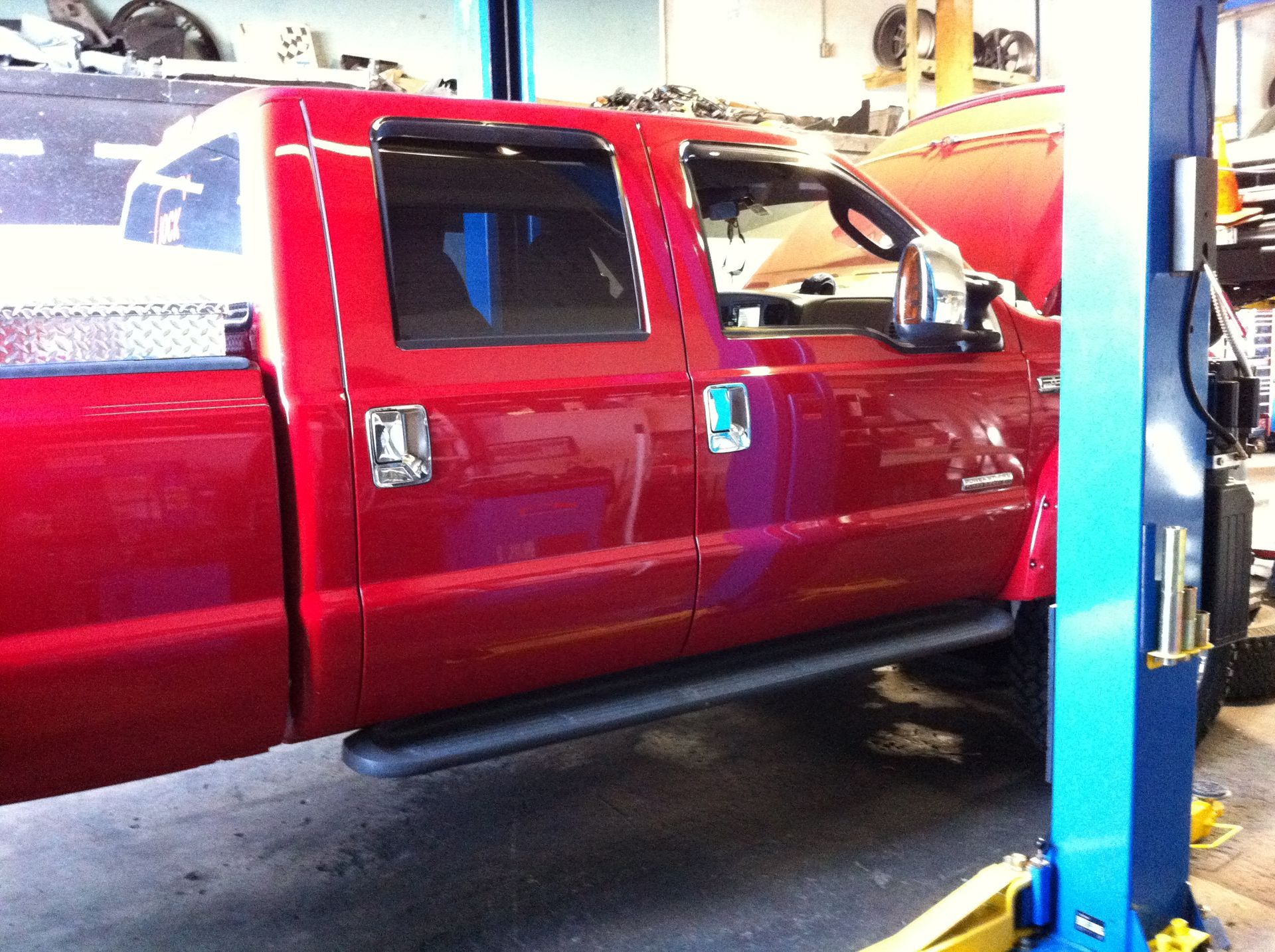 A red truck is on a lift in a garage