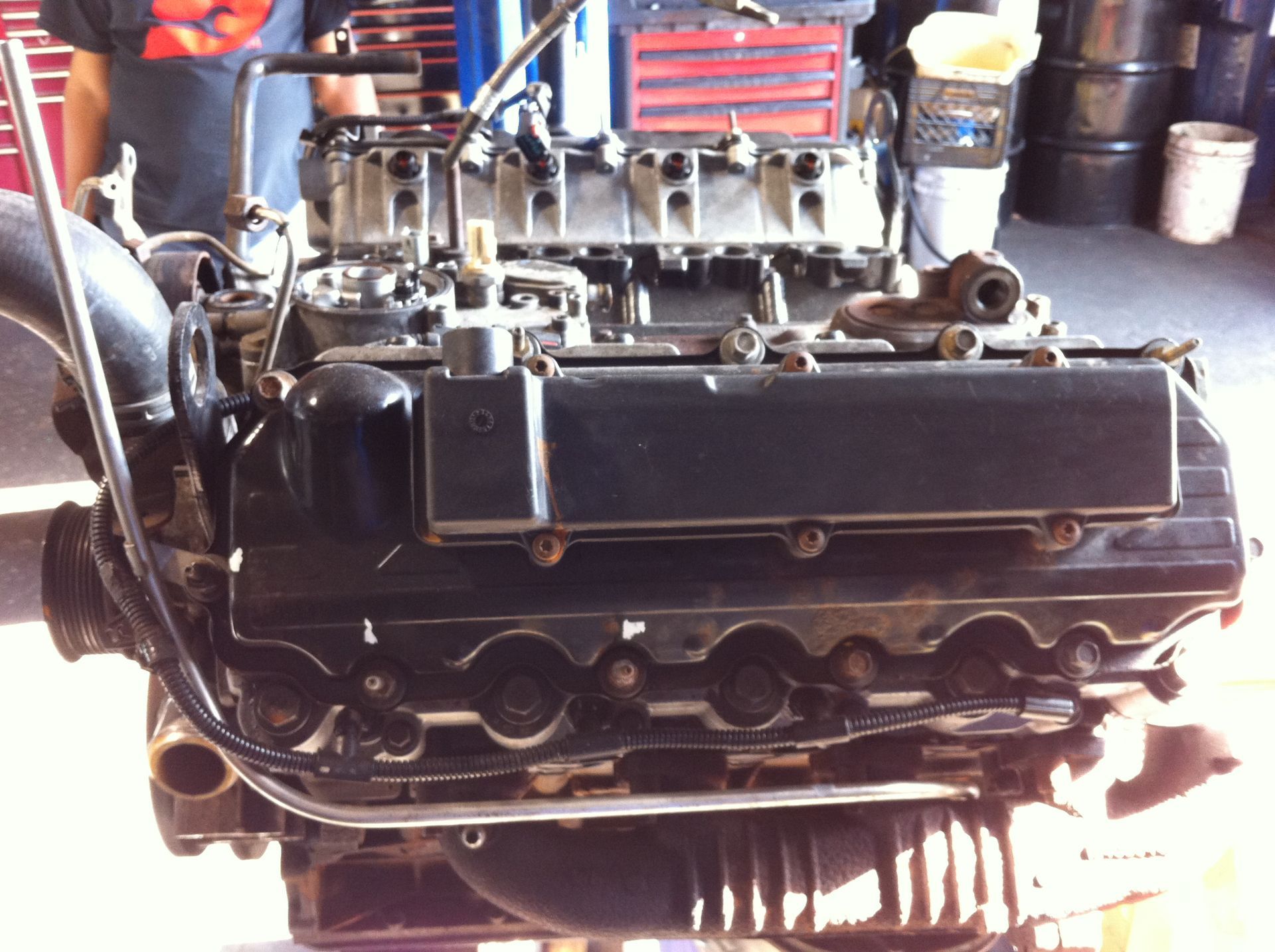 A man in a black shirt stands behind a black engine