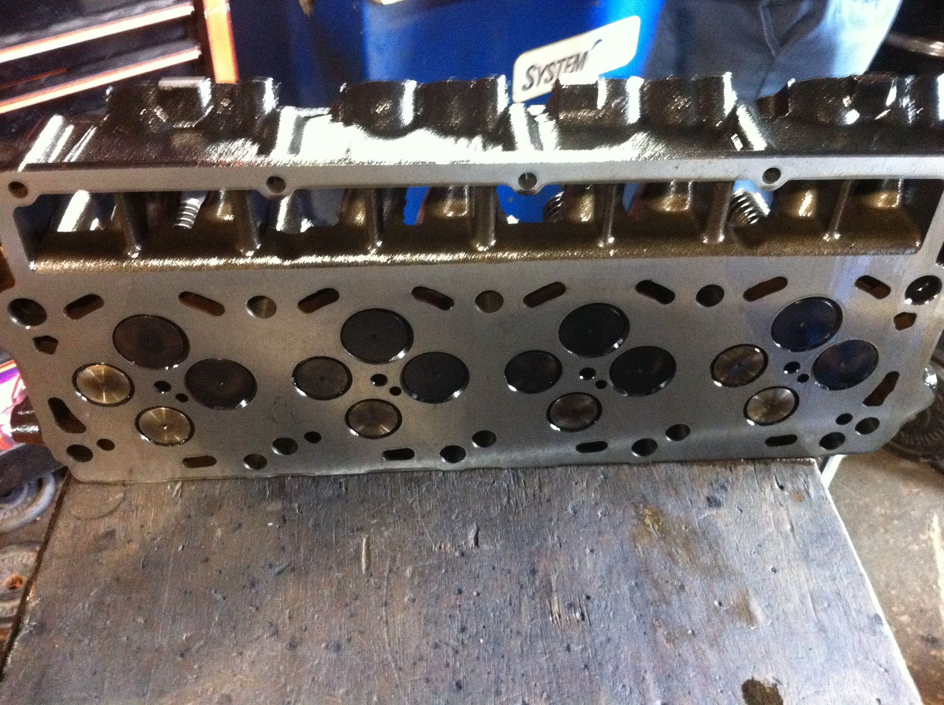 A cylinder head is sitting on a table next to a blue container that says spark