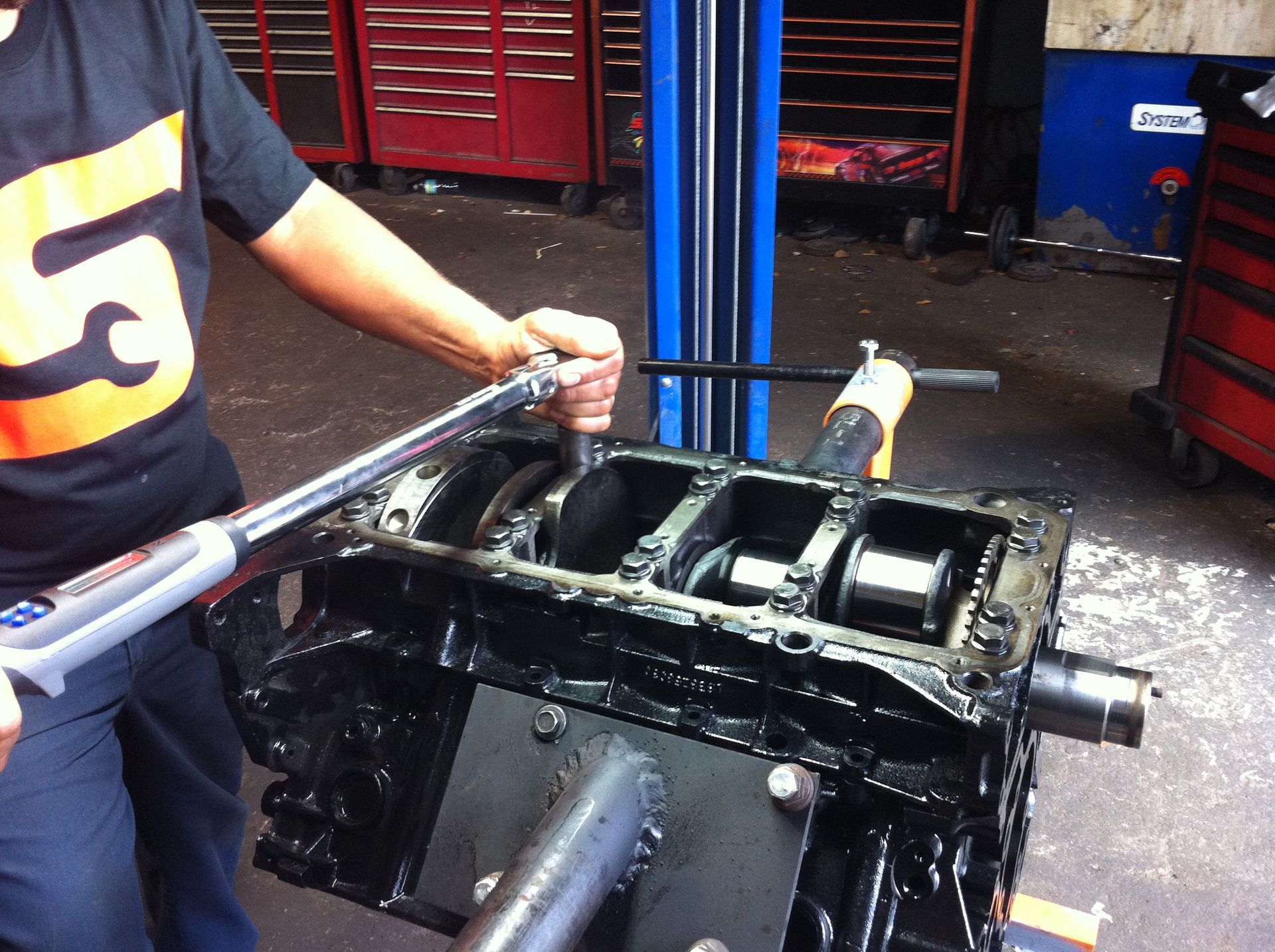 A man wearing a snap on shirt is working on a car engine