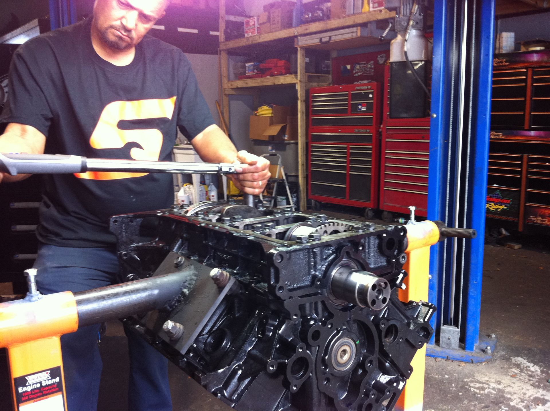 A man wearing a snap on shirt is working on a engine