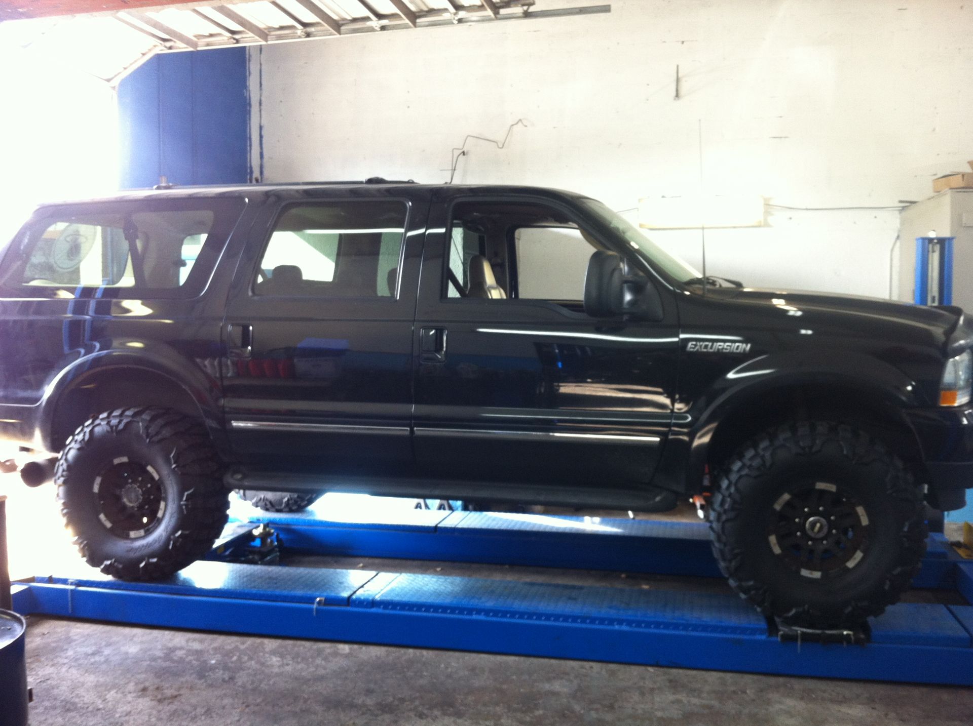 A black suv is on a lift in a garage