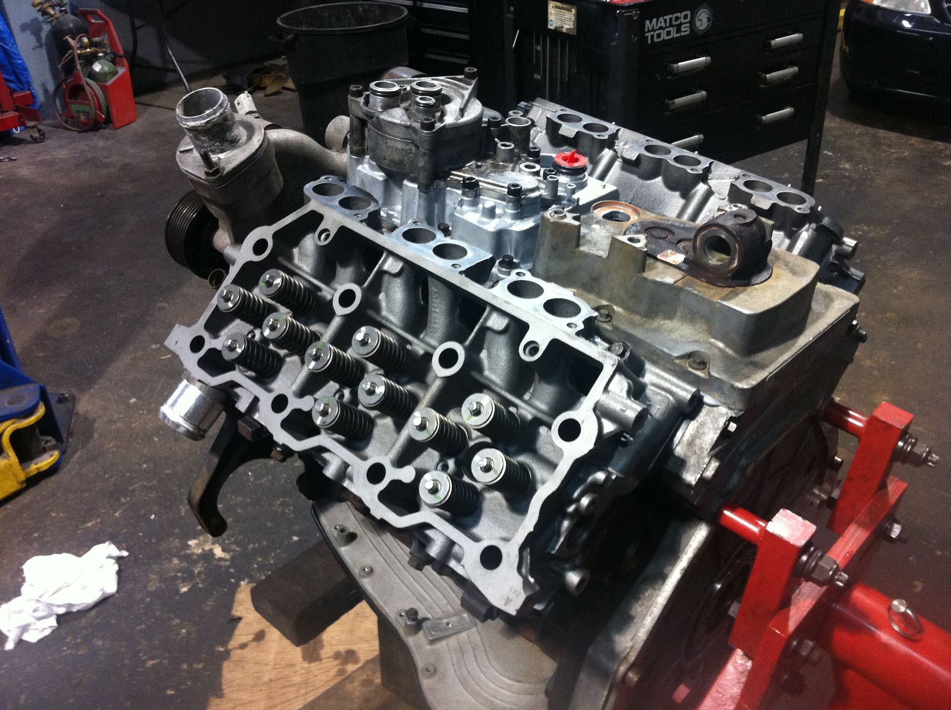 A car engine is sitting on top of a wooden table in a garage.