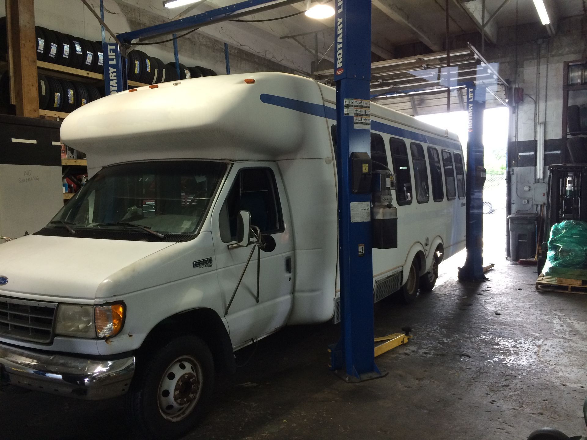 A white bus is on a lift in a garage