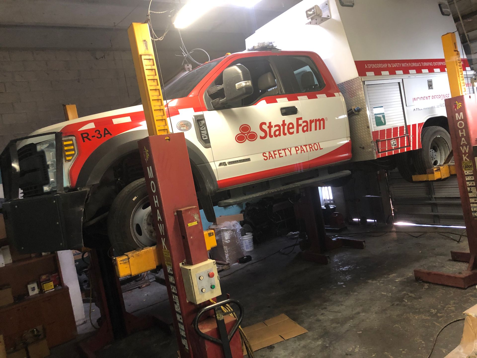 A state farm truck is on a lift in a garage