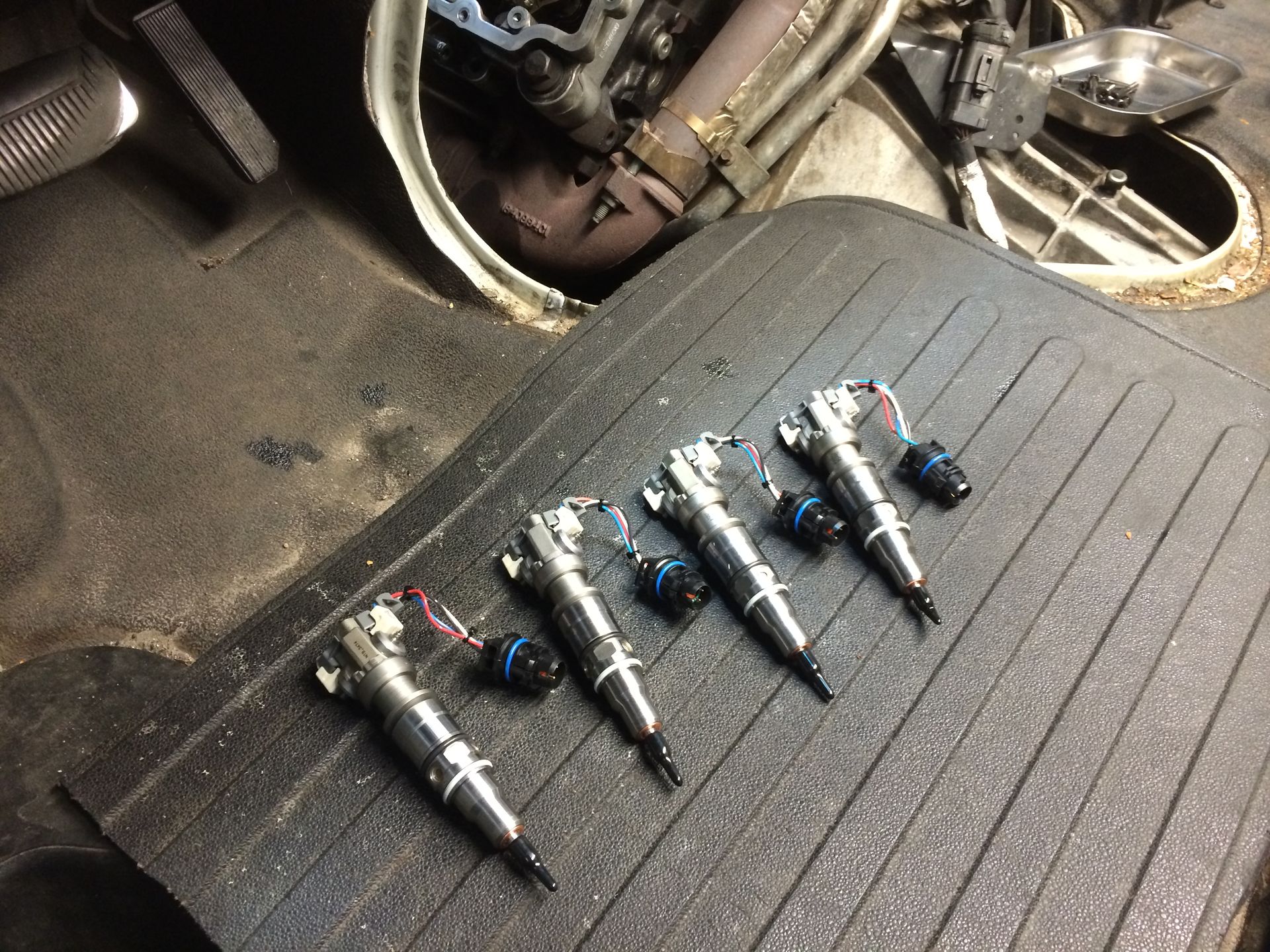 A bunch of fuel injectors are sitting on a black mat.