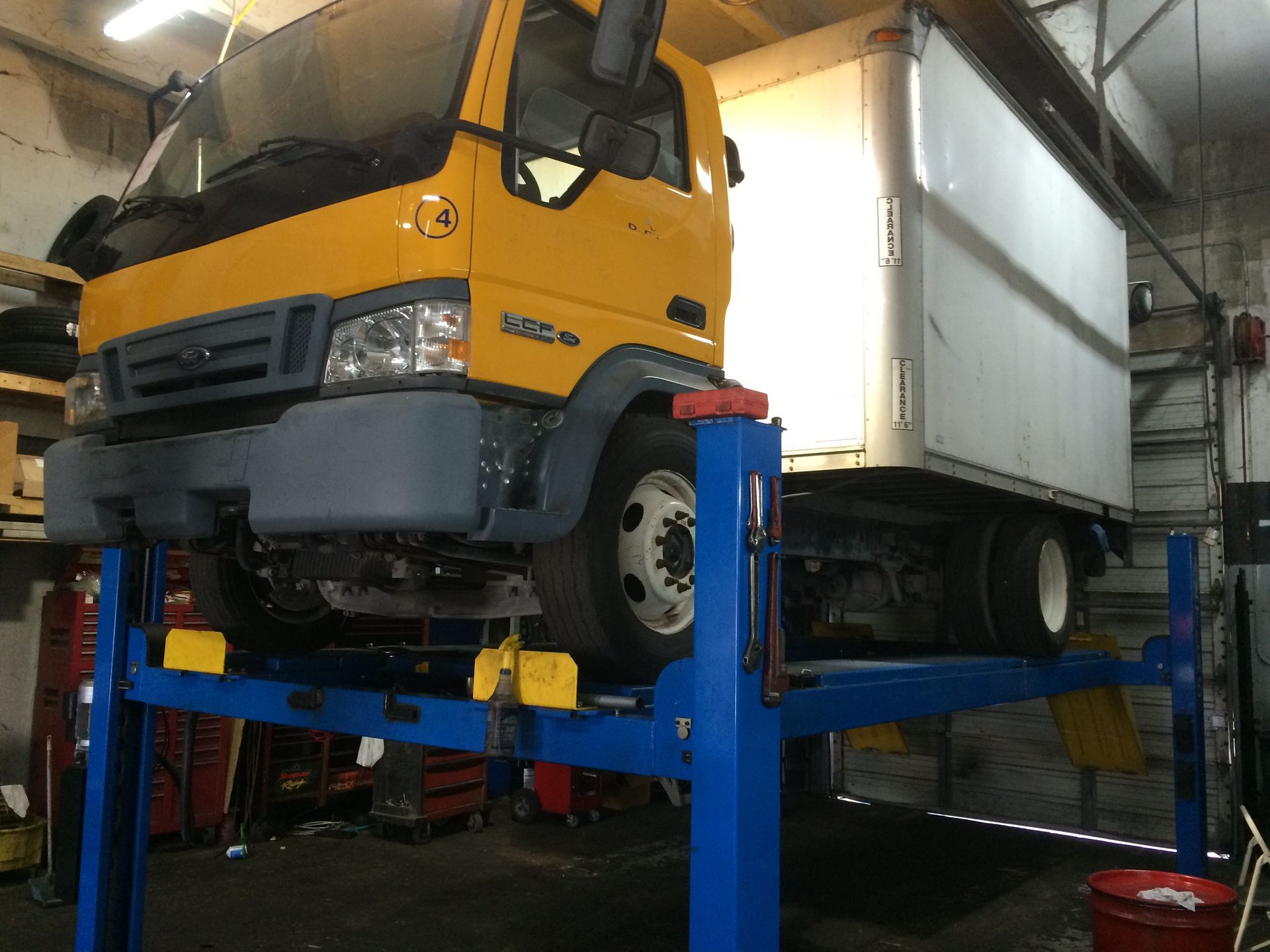 A yellow truck is sitting on a blue lift in a garage.