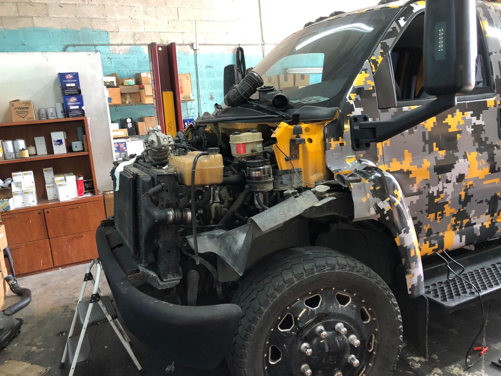 A truck with its hood open is sitting in a garage.