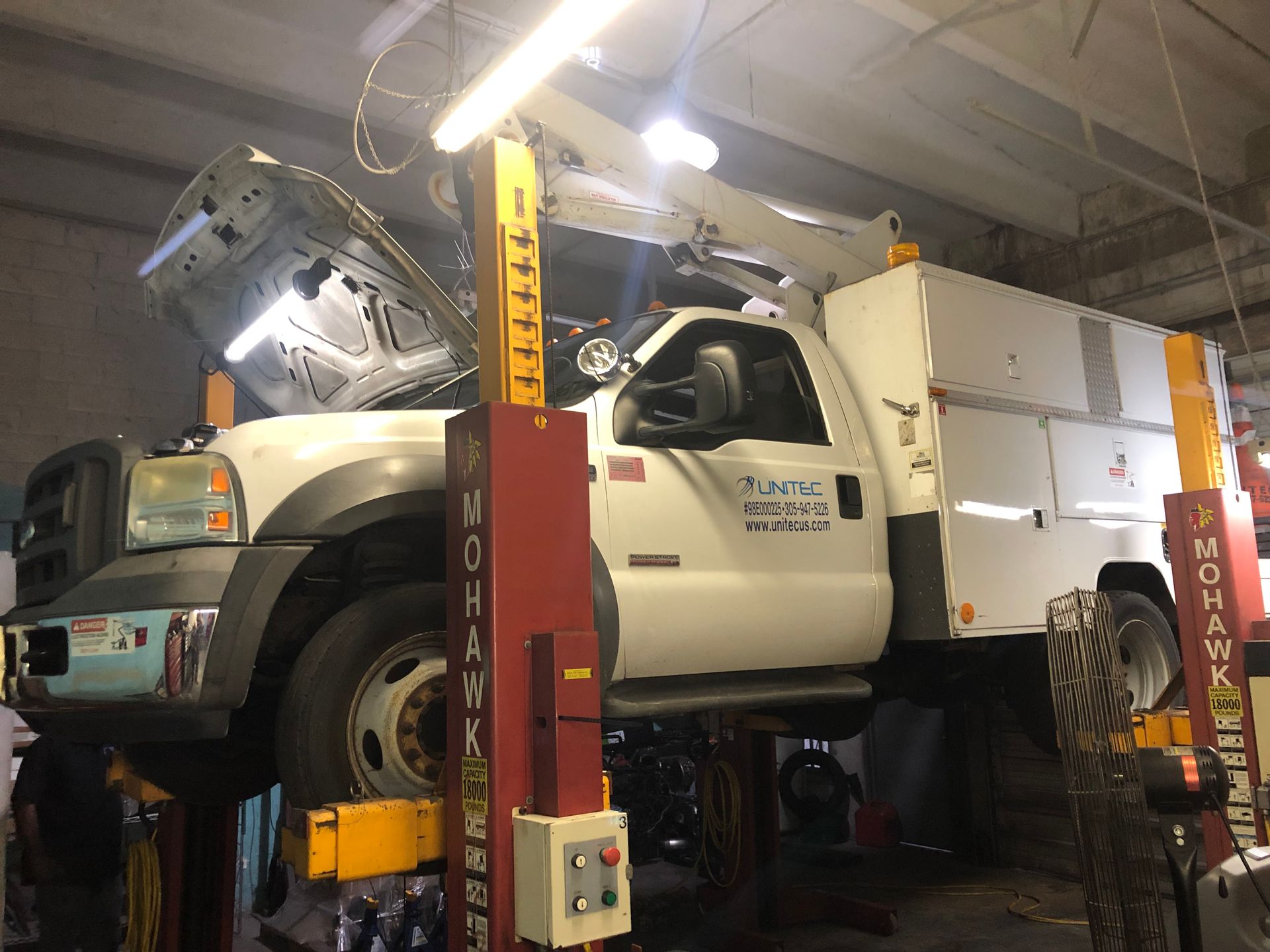 A white truck is sitting on a lift in a garage.