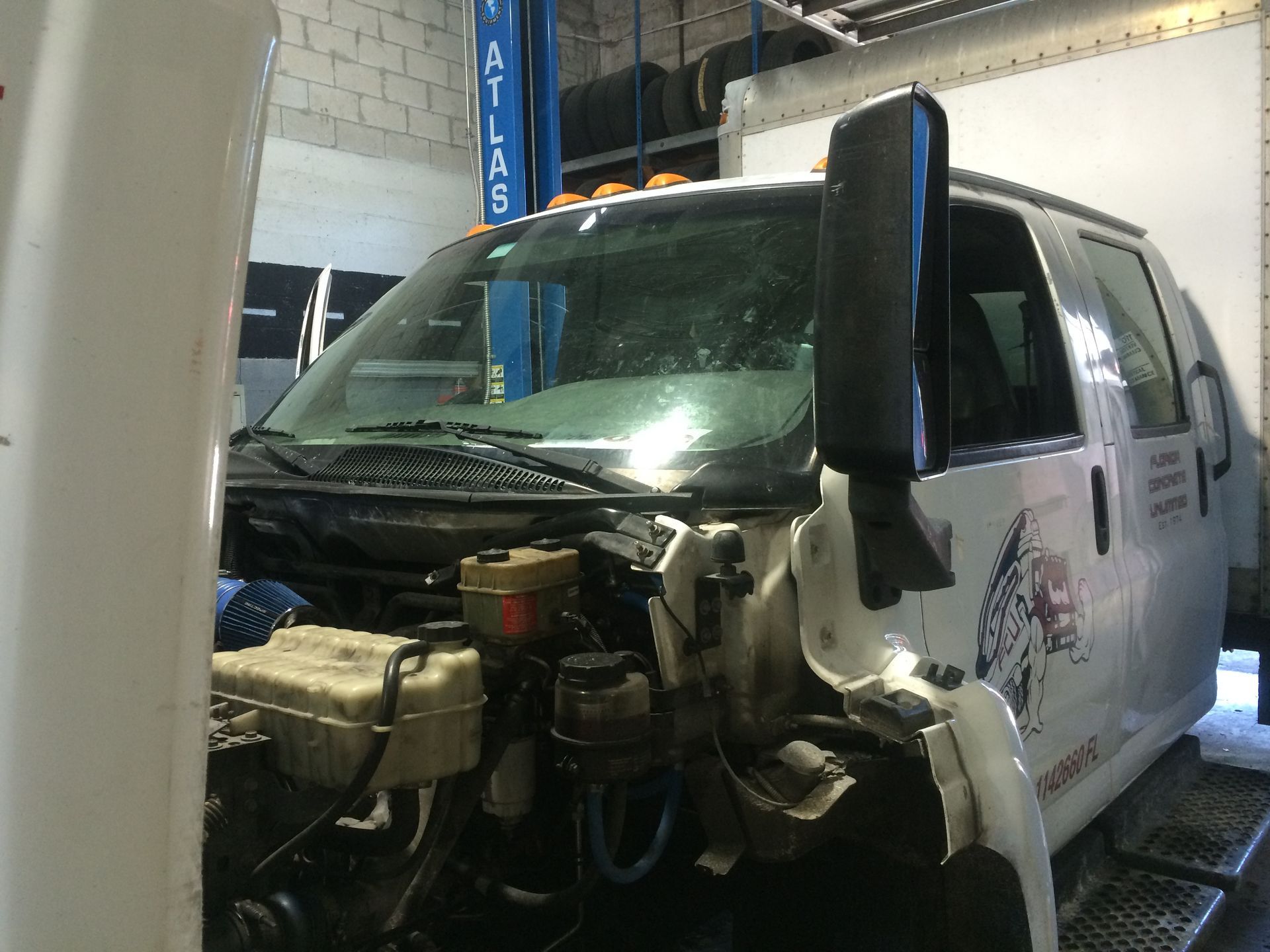 A white van with the hood open in a garage