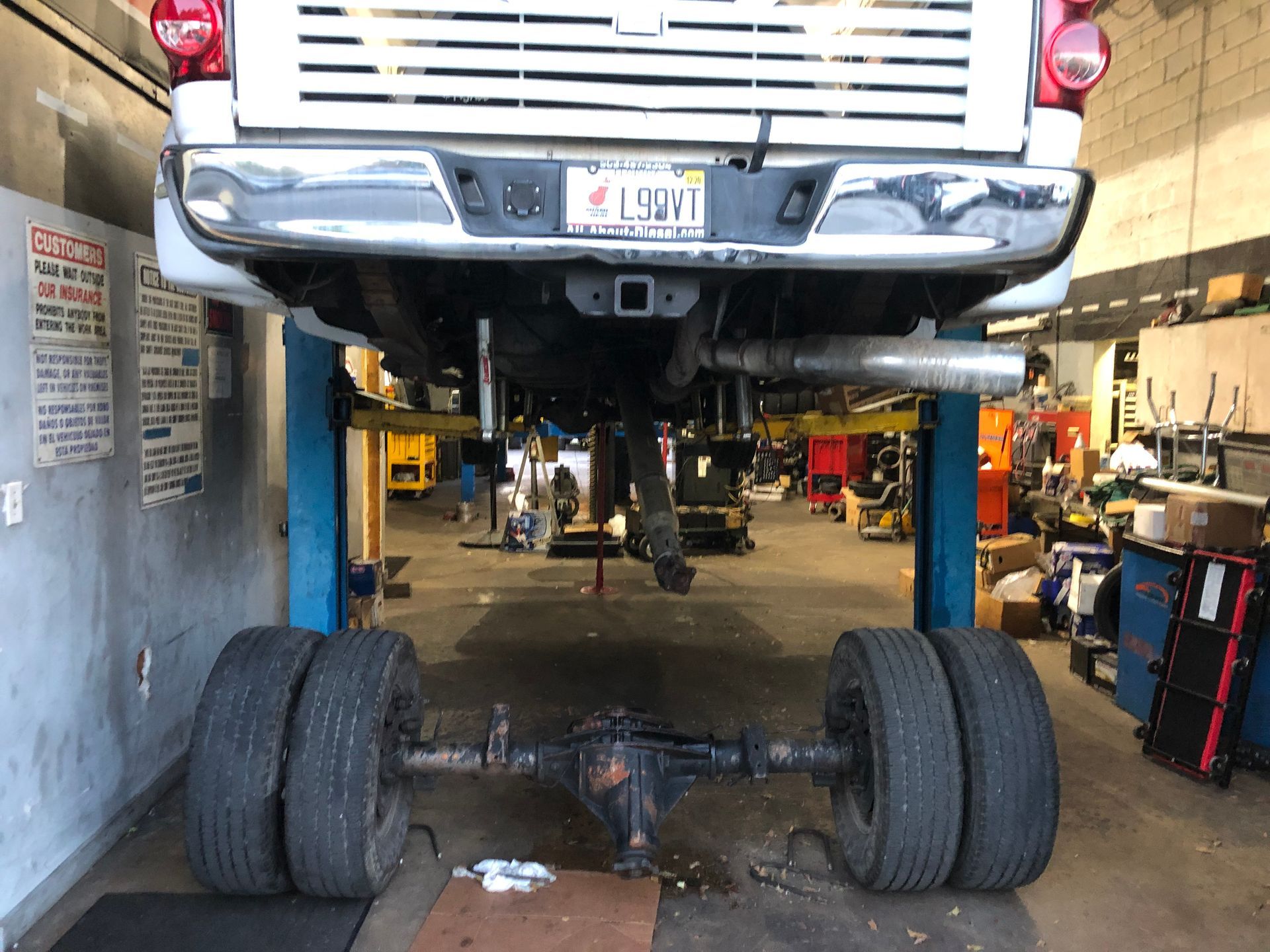 A truck is sitting on a lift in a garage.