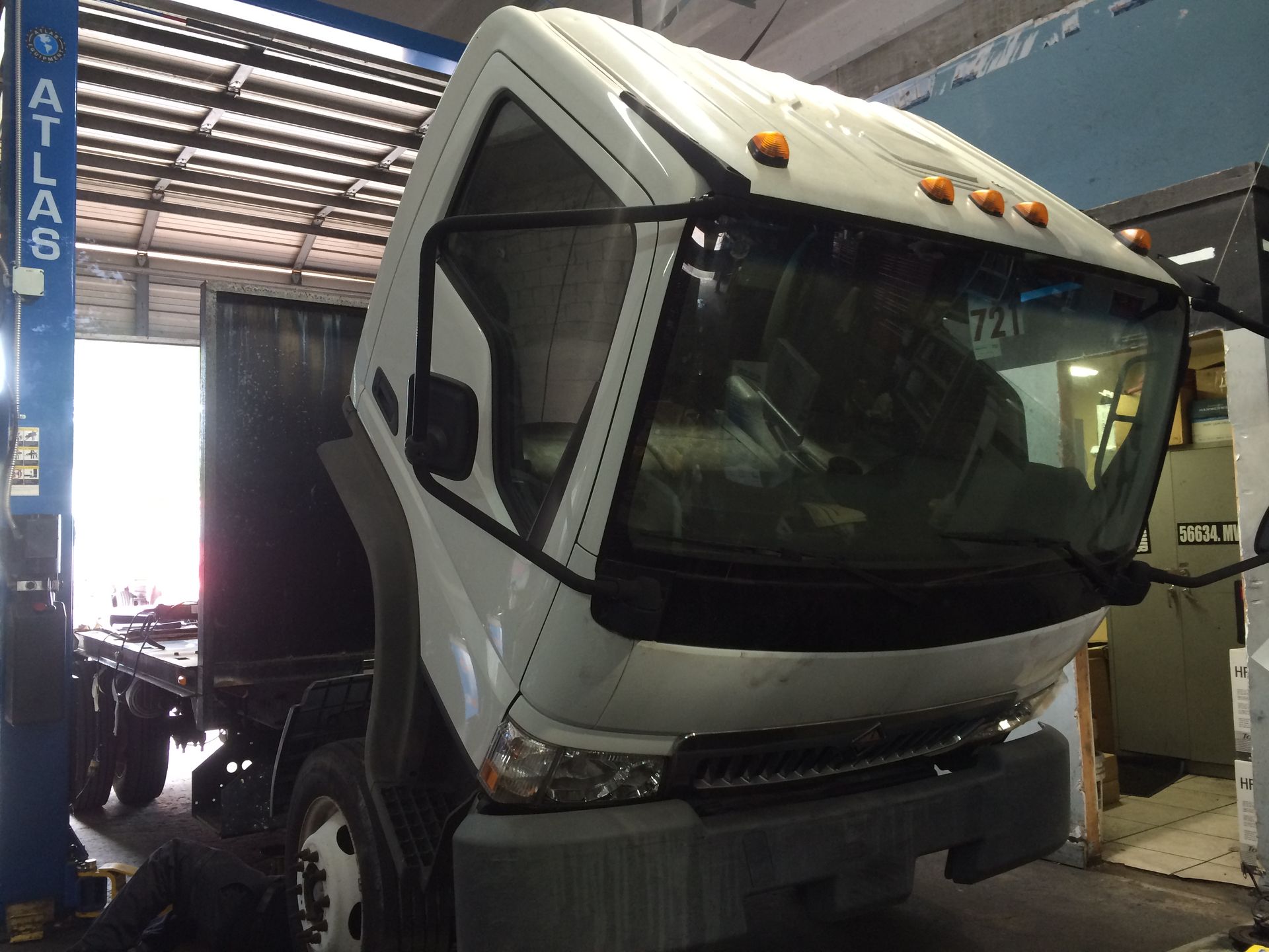 A white truck is sitting on a lift in a garage.